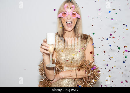 Ältere Frau mit goldenen Kleid und flmingo geformte Gläser, celebtraing Silvester Stockfoto