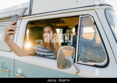 Lächelnde Frau mit einem selfie in einem Reisemobil mit Mann, der Stockfoto