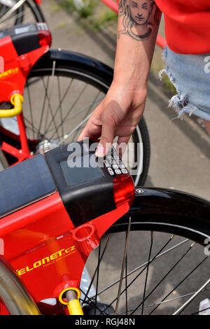 Junge Frau eingabe code Fahrrad mit Smartphone nach der Registrierung einstellen Stockfoto