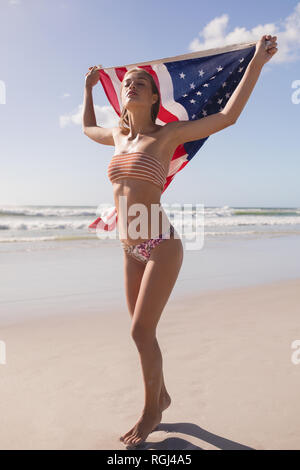 Junge Frau mit wehende Amerikanische Flagge am Strand Stockfoto