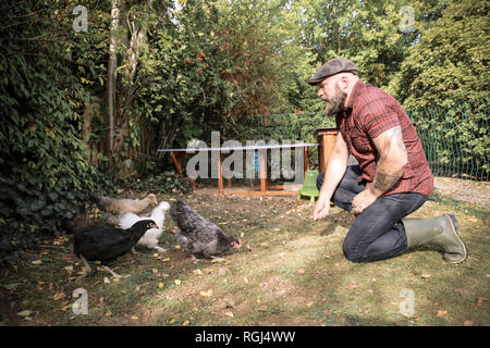 Mann in seinem eigenen Garten, mann Fütterung freie Hühner Stockfoto