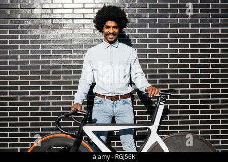 Mitte der erwachsene Mann stand vor der schwarzen Wand, sein Fahrrad Holding Stockfoto