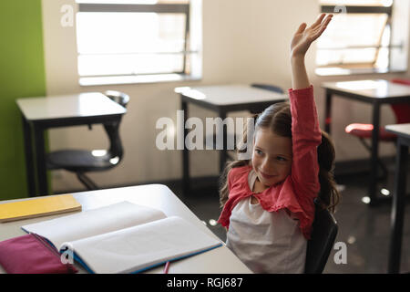 Schulmädchen Erhöhung Hand im Klassenzimmer Stockfoto