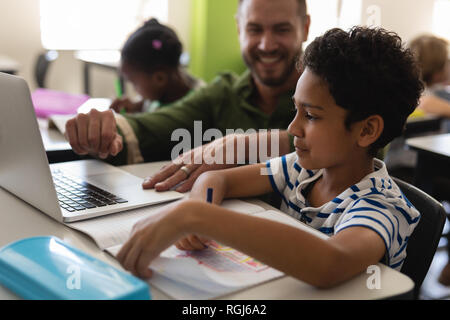 In der Nähe der Jugendlichen Schule Lehrer helfen jungen mit Studie über Laptop im Klassenzimmer Stockfoto