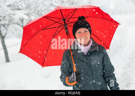 Glückliche Frau mit rotem Dach genießen Winter Schnee draußen im Park Stockfoto