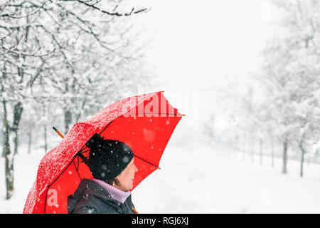 Glückliche Frau mit rotem Dach genießen Winter Schnee draußen im Park Stockfoto