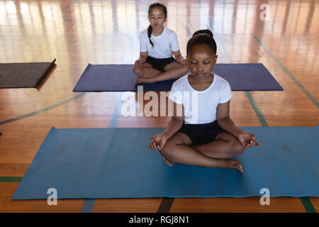 Schoolkids Yoga und Meditation über Yoga Matte in der Schule Stockfoto