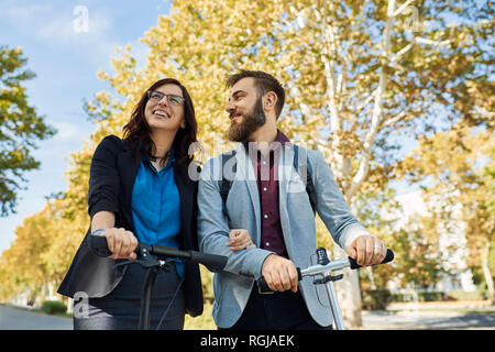 Happy Geschäftsmann und Geschäftsfrau mit scooters Stockfoto