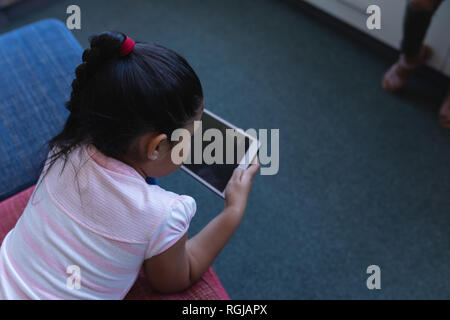 Schulmädchen studieren auf digitalen Tablet beim liegen auf der Couch in der Schule Bibliothek Stockfoto