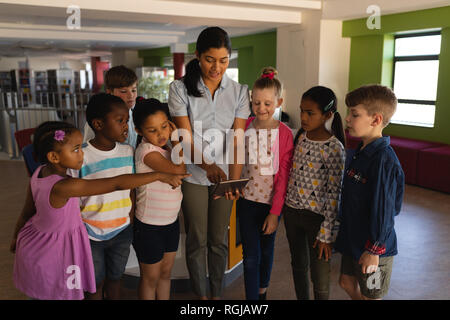 Vorderansicht der weiblichen Lehrer Lehre schoolkids auf digitalen Tablet in der Schule Stockfoto