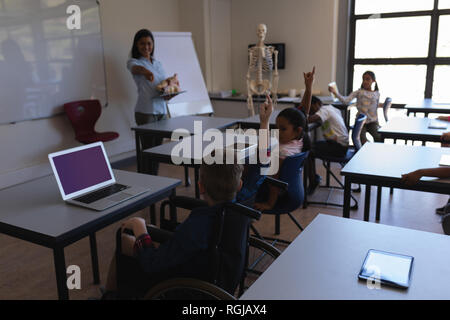 Vorderansicht der Lehrerin zeigt mit seinem Finger in Richtung schoolkid im Klassenzimmer der Volksschule Stockfoto