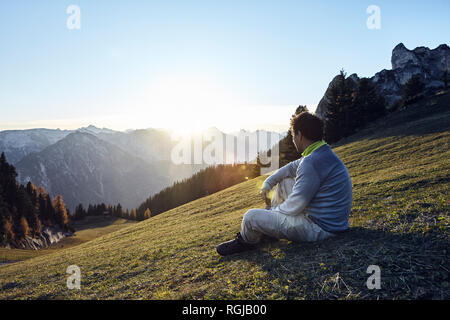Österreich, Tirol, Rofangebirge, Wanderer sitzen auf Wiese bei Sonnenuntergang Stockfoto