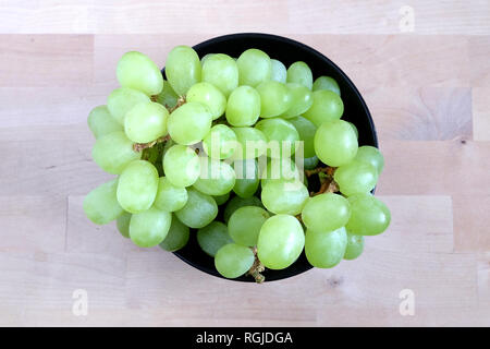 Menge reif grüne Beeren auf bunche in Schwarze runde Schüssel auf Holz- hintergrund Top View close up Stockfoto