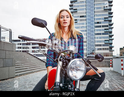 Portrait von selbstbewussten jungen Frau, die auf dem Motorrad Stockfoto