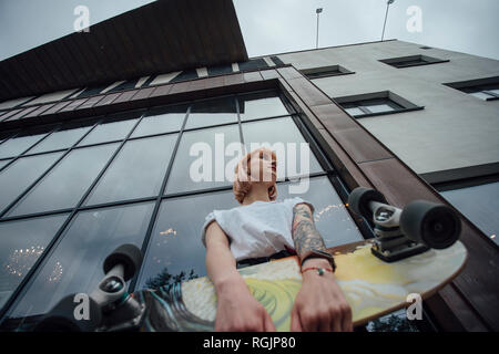 Junge Frau mit Carver skateboard außerhalb eines Gebäudes Stockfoto