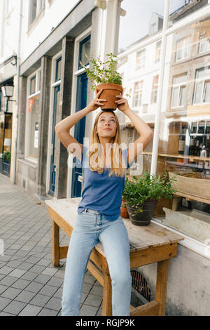 Niederlande, Maastricht, junge Frau balancing Blumentopf auf den Kopf in der Stadt Stockfoto
