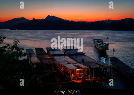 Sonnenuntergang in Luang Prabang auf den Mekong. Touristische und Haus Boote im Wasser. Himmel in Flammen. Stockfoto