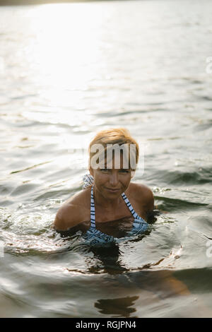 Porträt der lächelnde Frau schwimmen in einem See Stockfoto