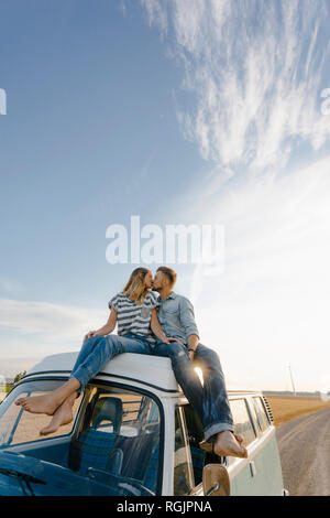 Paar küssen Auf dem Dach von einem Wohnmobil in ländlichen Landschaft Stockfoto