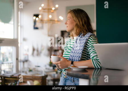 Junge Frau mit Tasse Kaffee und Laptop in einem Cafe Stockfoto