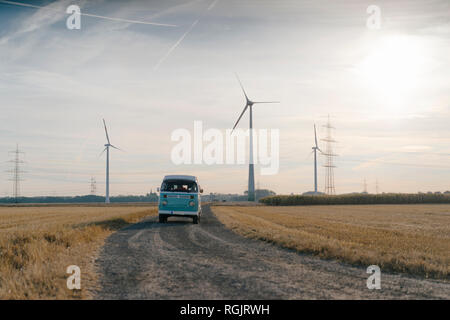 Wohnmobil in ländlichen Landschaft mit Windräder im Sonnenuntergang Stockfoto
