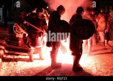 Eine Fackel wird gefeuert die Fackeln der Jarl Squad ans Licht, wie sie von März bis Lerwick vor der Kombüse auf Feuer auf den Shetland Inseln während der Up Helly Aa Wikinger Fest gesetzt wird. Mit Ursprung in den 1880er Jahren, das Festival feiert den Shetland nordischen Erbe. Stockfoto