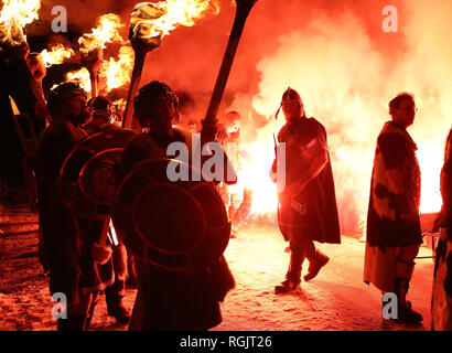 Eine Fackel wird gefeuert die Fackeln der Jarl Squad ans Licht, wie sie von März bis Lerwick vor der Kombüse auf Feuer auf den Shetland Inseln während der Up Helly Aa Wikinger Fest gesetzt wird. Mit Ursprung in den 1880er Jahren, das Festival feiert den Shetland nordischen Erbe. Stockfoto