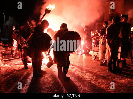 Eine Fackel wird gefeuert die Fackeln der Jarl Squad ans Licht, wie sie von März bis Lerwick vor der Kombüse auf Feuer auf den Shetland Inseln während der Up Helly Aa Wikinger Fest gesetzt wird. Mit Ursprung in den 1880er Jahren, das Festival feiert den Shetland nordischen Erbe. Stockfoto