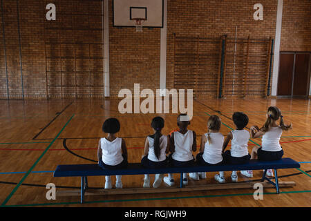 Schoolkids sitzt auf der Bank am Basketballplatz Stockfoto