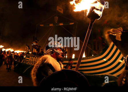 Mitglieder der Jarl Squad März neben der Küche, wie sie durch die lerwick vor der Kombüse auf Feuer auf den Shetland Inseln während der Up Helly Aa Wikinger Fest gesetzt wird. Mit Ursprung in den 1880er Jahren, das Festival feiert den Shetland nordischen Erbe. Stockfoto