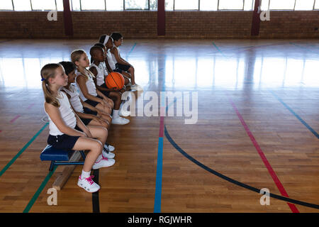 Schoolkids sitzt auf der Bank am Basketballplatz Stockfoto