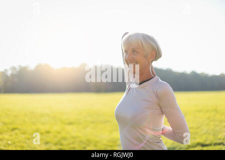 Lächelnd senior Frau Gymnastik auf ländlichen Wiese Stockfoto