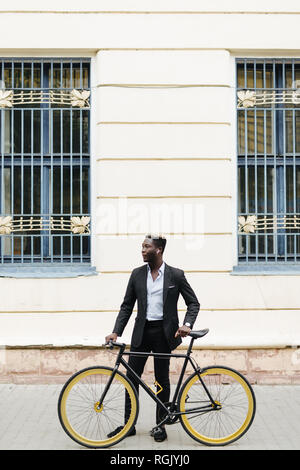 Schönen afrikanischen Mann, den ich auf der Straße mit dem Fahrrad. Afrikanischer Mann in casuals Walking im Freien in der Stadt mit dem Fahrrad. Stockfoto