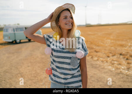 Glückliche junge Frau an Wohnmobil in ländlichen Landschaft Stockfoto