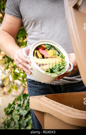 Reifer Mann werfen Küche Botschaften in bio-waste Container Stockfoto