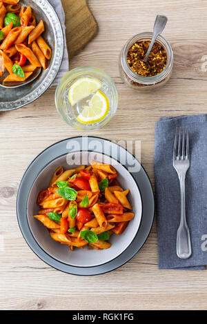 Penne mit Tomaten und Basilikum in der Schüssel von oben Stockfoto