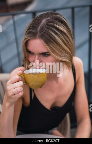 Junge Frau trinkt Kaffee auf der Dachterrasse Stockfoto