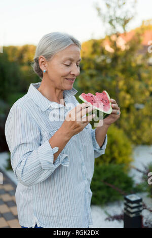 Ältere Frau, Essen, Wassermelone Schicht im Garten Stockfoto