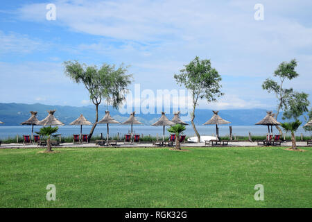 Stroh Sonnenschirme am Strand Skadarsee. Albanien und Montenegro Grenze. Stockfoto