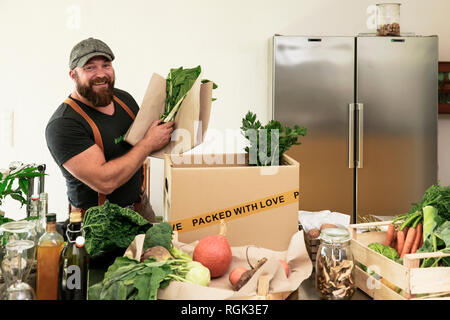 Reifer Mann mit Lieferservice Verpackung Bio Gemüse in Kartons Stockfoto