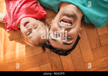 Portrait von Vater und Tochter auf dem Boden liegend zu Hause Spaß Stockfoto