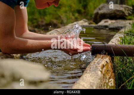 Deutschland, Oberbayern, Chiemgau, junger Mann erfrischend an einem Brunnen Stockfoto