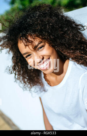 Porträt von lachender Junge Frau mit lockigem Haar Stockfoto