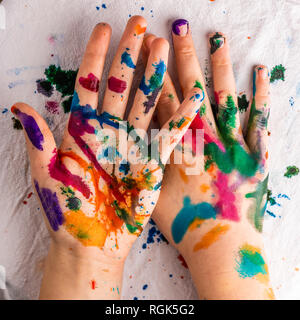 Die Hände des Kindes sind in Rot, Rosa, Gelb, Orange, Rot, Blau, Grün und lila Tinte. Konzepte: Kunst, Bildung, Spielen, Aquarell, Malen mit den Fingern Stockfoto
