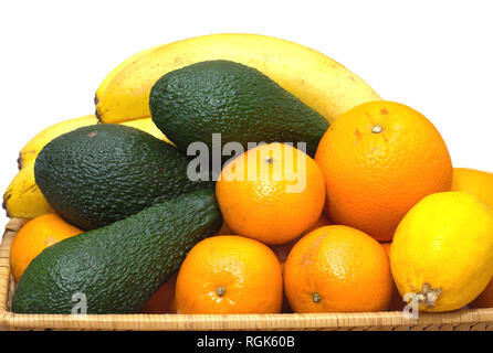 Stillleben mit tropischen Früchte: Bananen, Avocados, Zitronen, Orangen und Mandarinen liegen auf einem braunen Rattanmöbeln Fach isoliert auf Weiss. Vordere Foto closeup Stockfoto