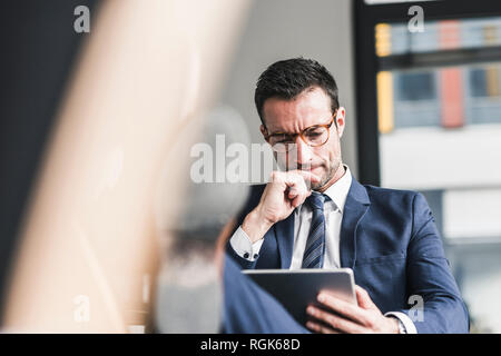 Geschäftsmann mit digitalen Tablet, im Büro mit Füßen bis Stockfoto