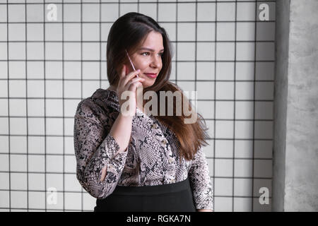 Close up Junge Büro Frau mit jemand sprechen auf ihrem Mobiltelefon, während sie in die Ferne mit glücklichen Gesichtsausdruck Stockfoto
