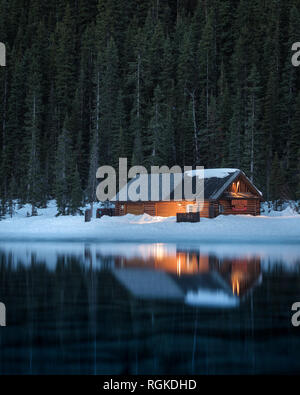 Dämmerung Zeit. Reflexionen der kleinen Boot Haus oder Hütte in Gewässern des Sees Louie, Banff National Park, Alberta, Kanada Stockfoto