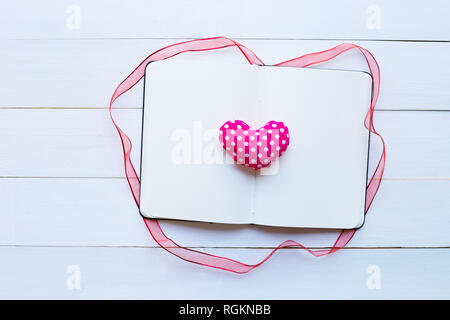 Tagebuch Notizbuch mit Valentine's Herz auf weißem Holz- Hintergrund. Ansicht von oben Stockfoto