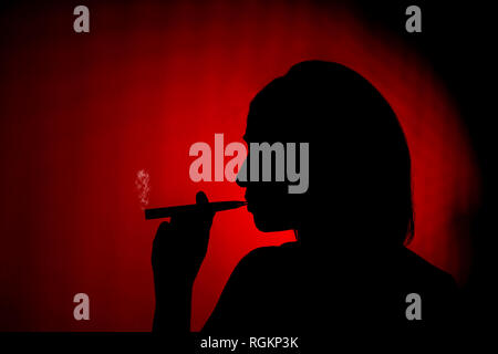 Silhouette einer Frau das Rauchen einer ecig auf rotem Hintergrund Stockfoto